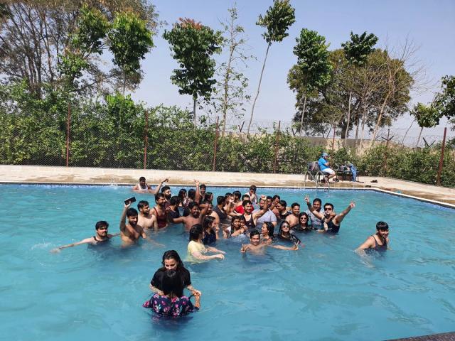 Colleagues gathered together in the outdoor swimming pool during a corporate outing at Rangmanch Farms in Gurugram, near Delhi