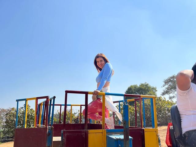 A woman boarding a colourful tractor trolley ride under a clear sky during a day outing at Rangmanch Farms in Gurugram, near Delhi