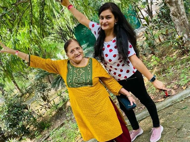 Two women posing for a selfie with arms outstretched on a tree-lined garden path during a family day outing at Rangmanch Farms in Gurugram, near Delhi