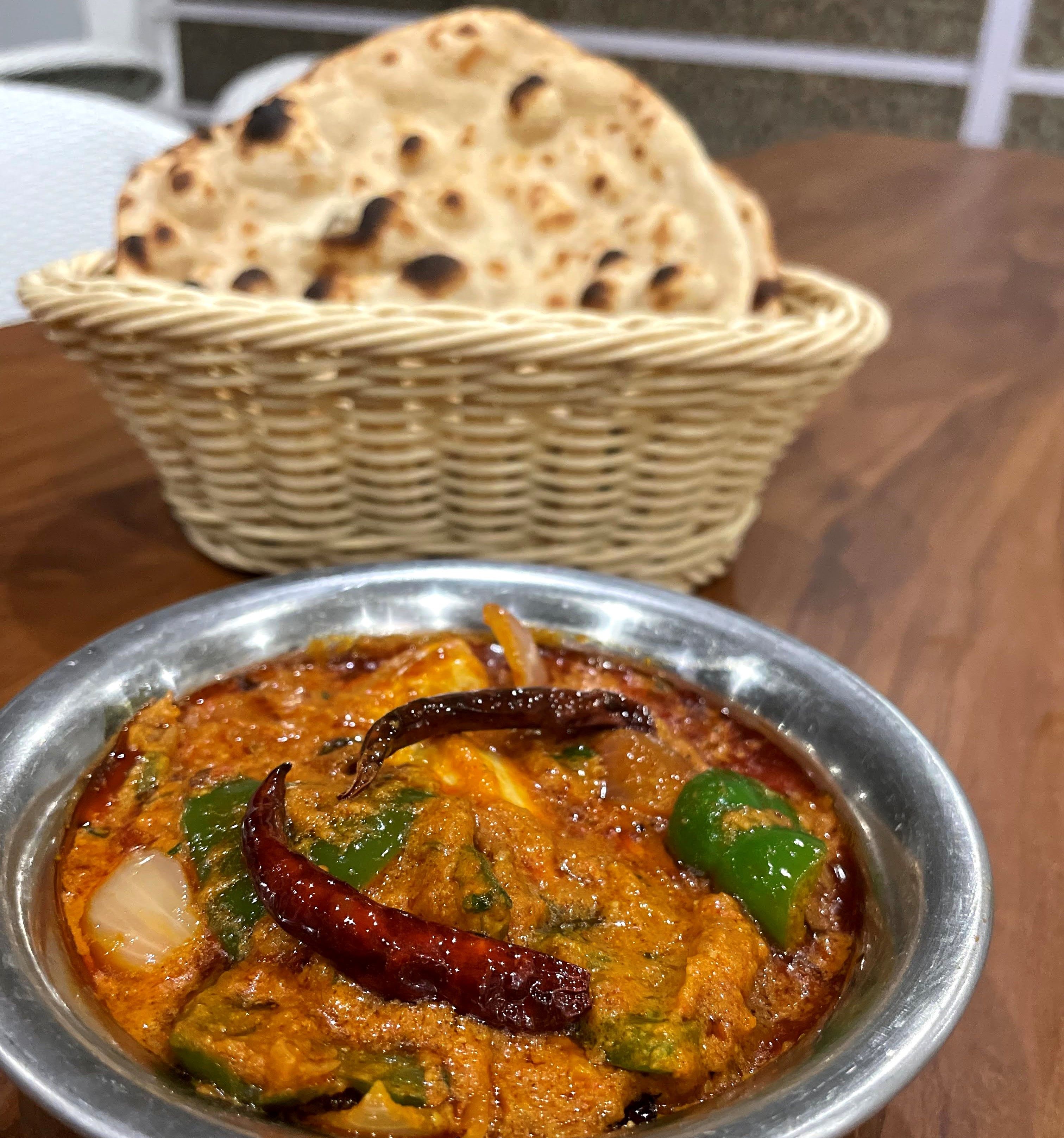 Main course curry in a bowl served with a basket of tandoori roti from the buffet at Rangmanch Farms, an outdoor event venue in Gurugram near Delhi