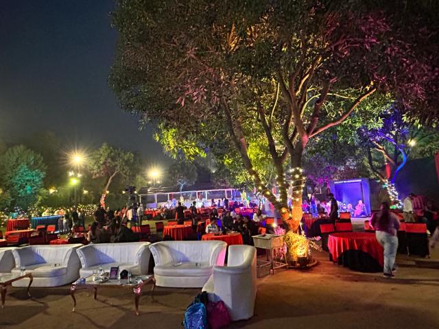 Lounge seating under fairy-lit trees at an evening corporate party — outdoor corporate event venue, Rangmanch Farms, Gurugram