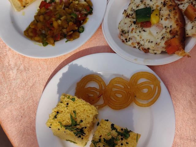Plates of starters, pizza and desserts including jalebi served on a table during an event at Rangmanch Farms, an outing venue in Gurugram near Delhi