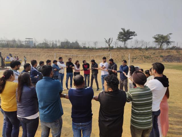 Colleagues in a circle during a team building activity on the open field — corporate team building venue in Gurugram