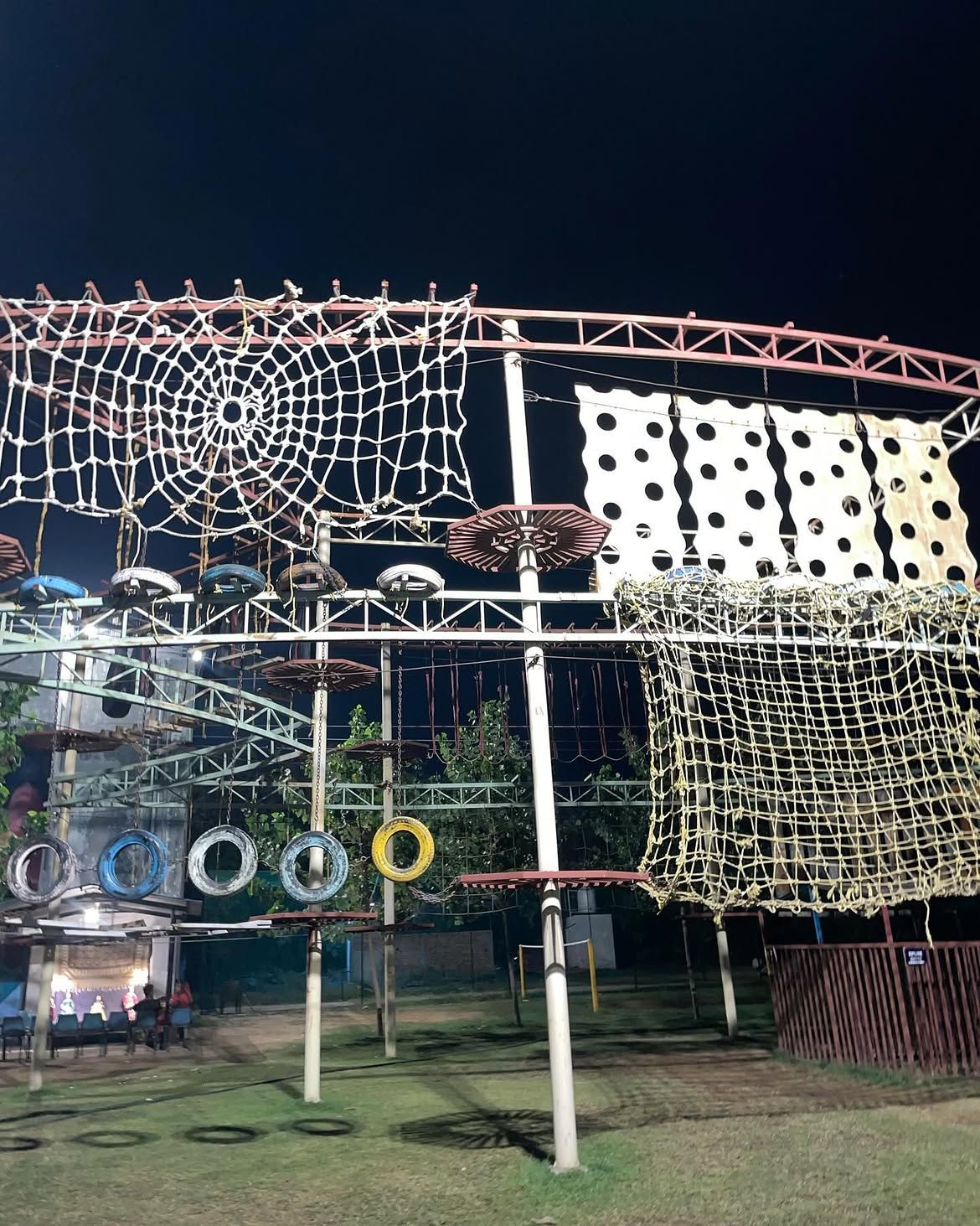 Outdoor rope and net obstacle course with hanging tyres lit up at night at Rangmanch Farms, an adventure and team building venue in Gurugram near Delhi