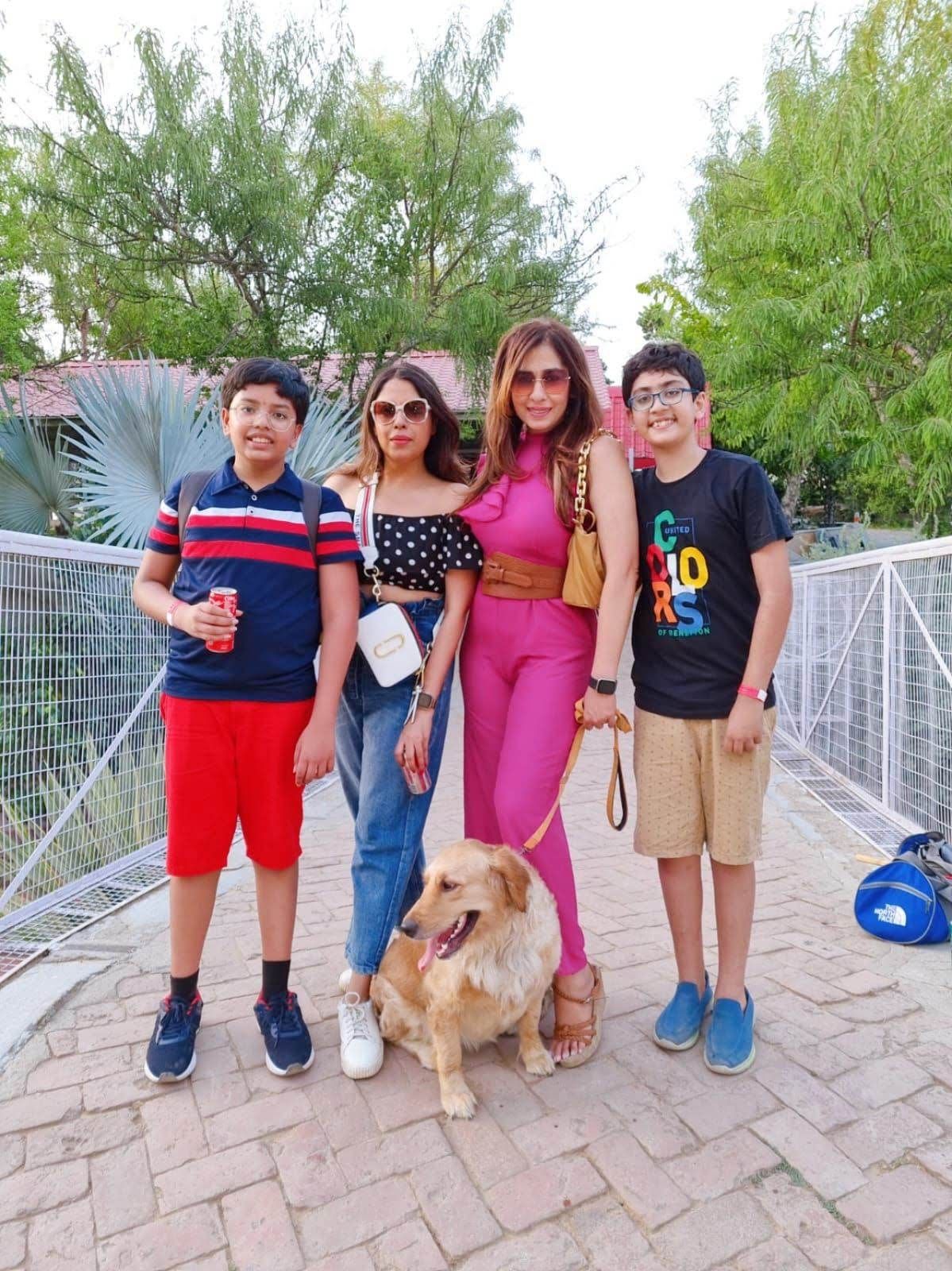 A family with a golden retriever posing on a brick pathway during a day outing at Rangmanch Farms, a pet-friendly outdoor venue in Gurugram near Delhi