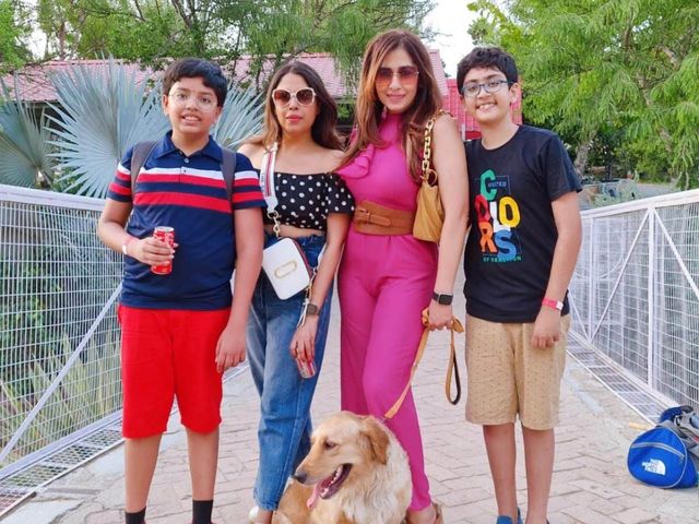 A family with a golden retriever posing on a brick pathway during a day outing at Rangmanch Farms, a pet-friendly outdoor venue in Gurugram near Delhi