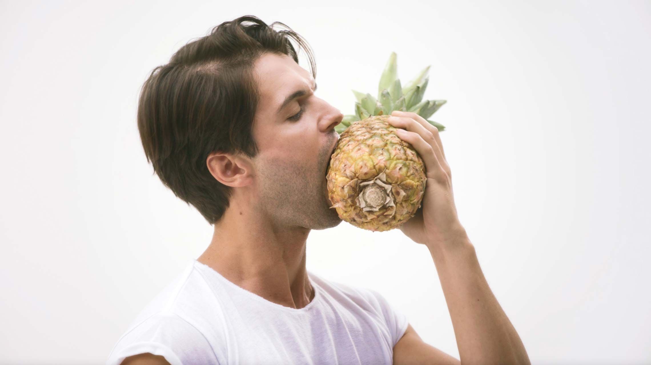 Photograph of a man biting a pineapple. Click to view one of the television advertisements.