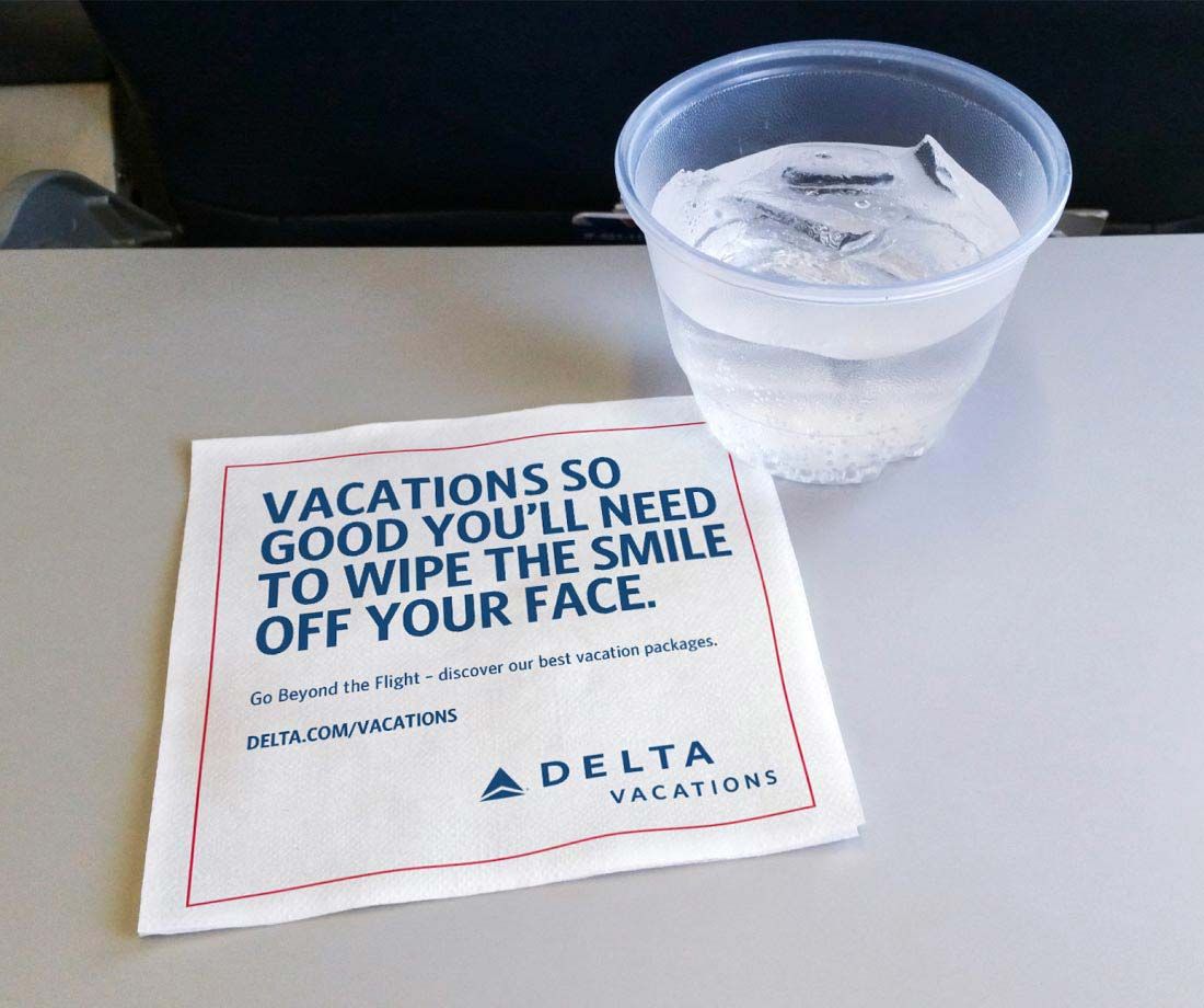Delta Vacations napkin on an airplane tray table.