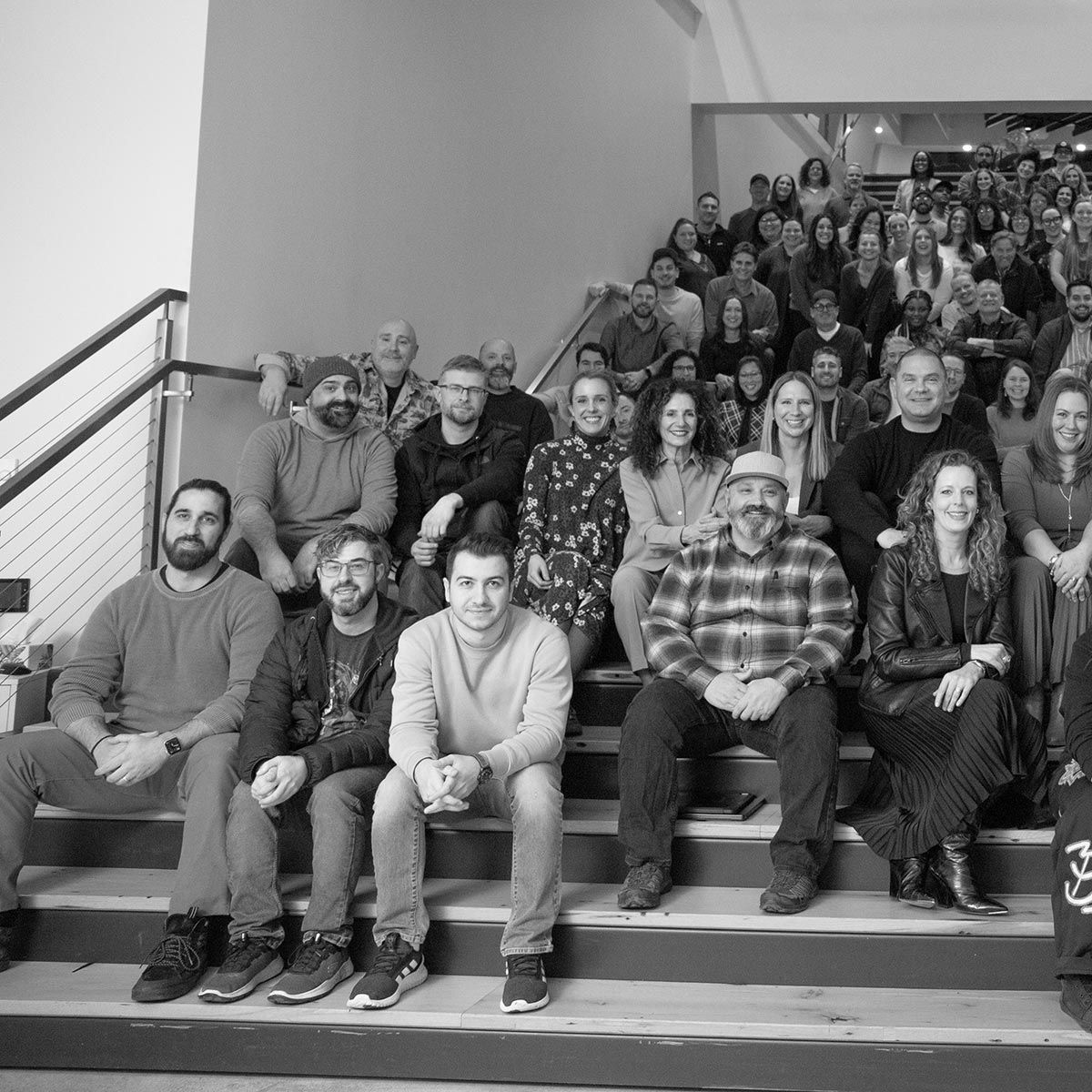 Photograph of the P+N employees seated on the stairs in the office.