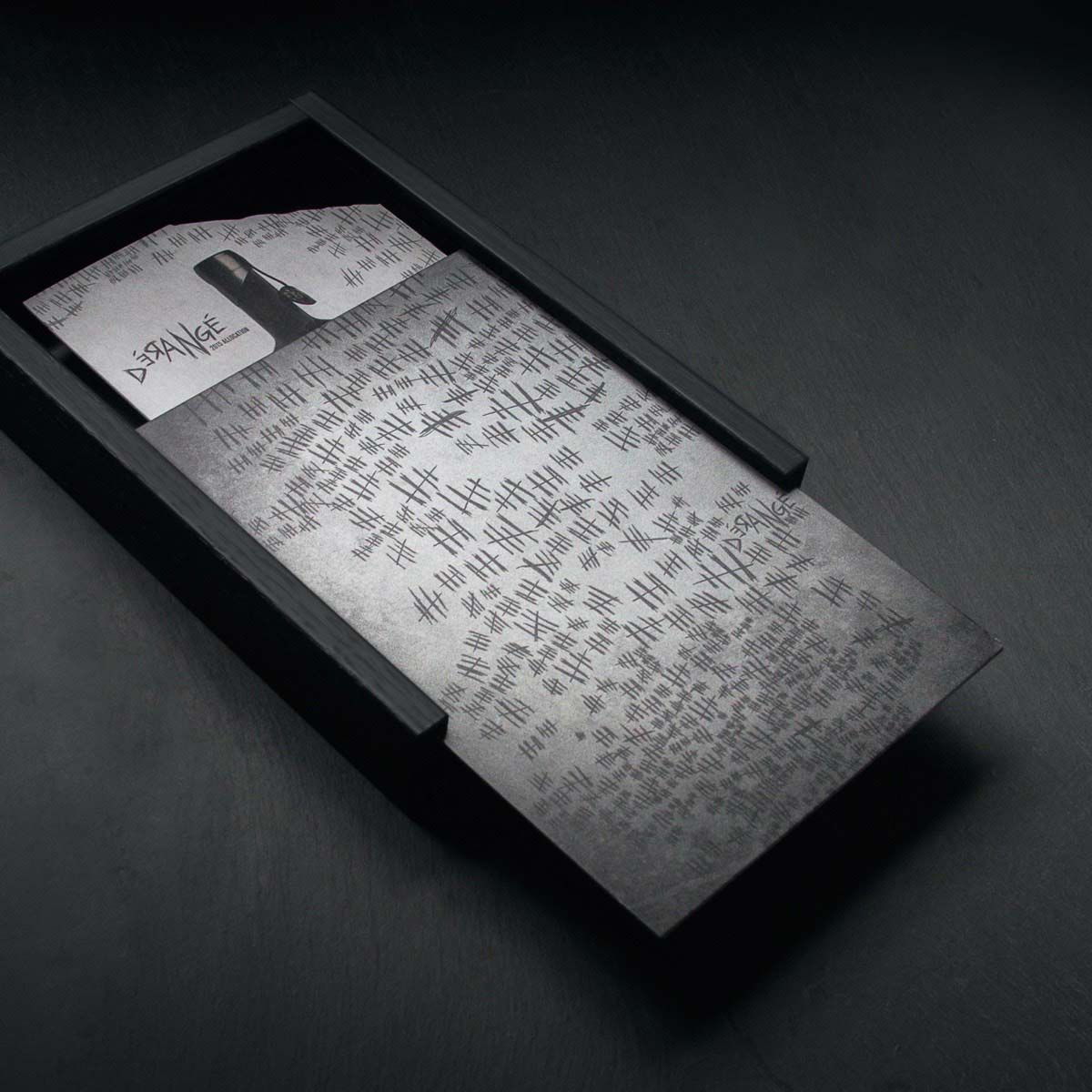 Image of a box with a sliding metal cover, engraved with multiple Roman numerals. The box is slightly open, revealing the Prisoner Wine collateral inside.