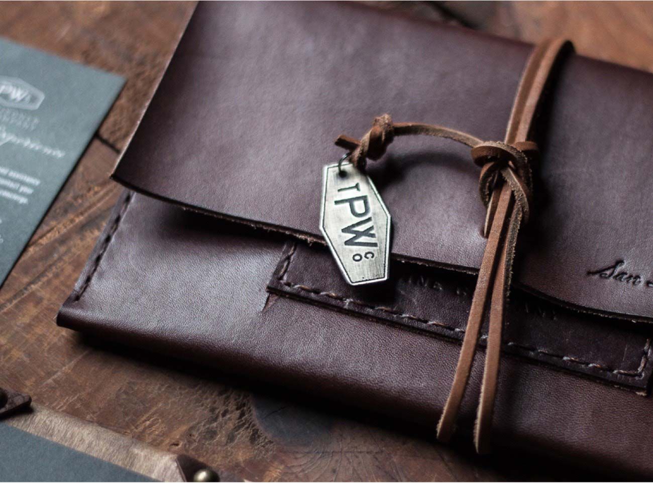 Photograph of a leather-bound satchel with The Prisoner Wine Company logo stamped on a metal tag.