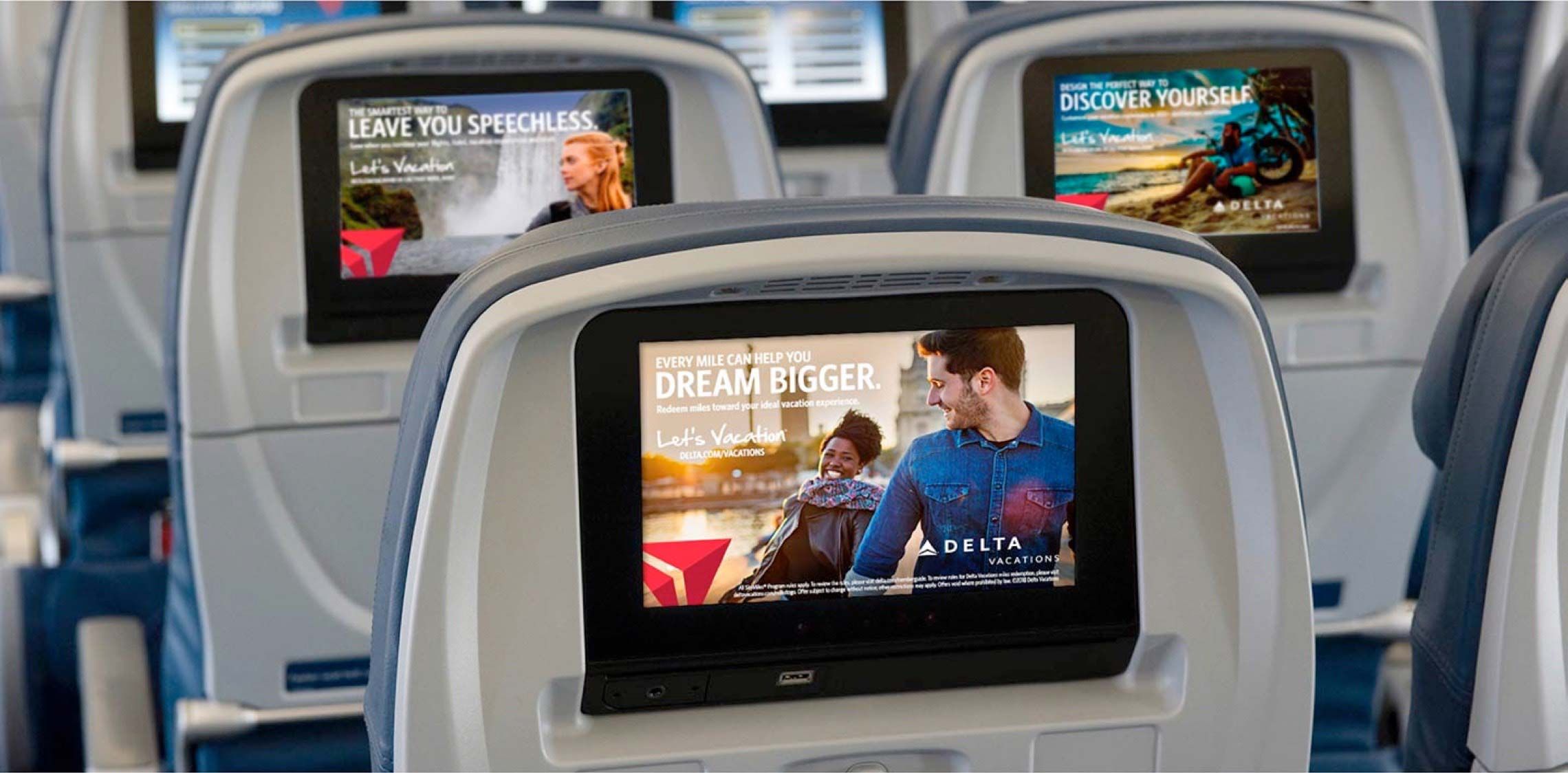 Delta Vacations advertisements playing on seat-backs in a plane.