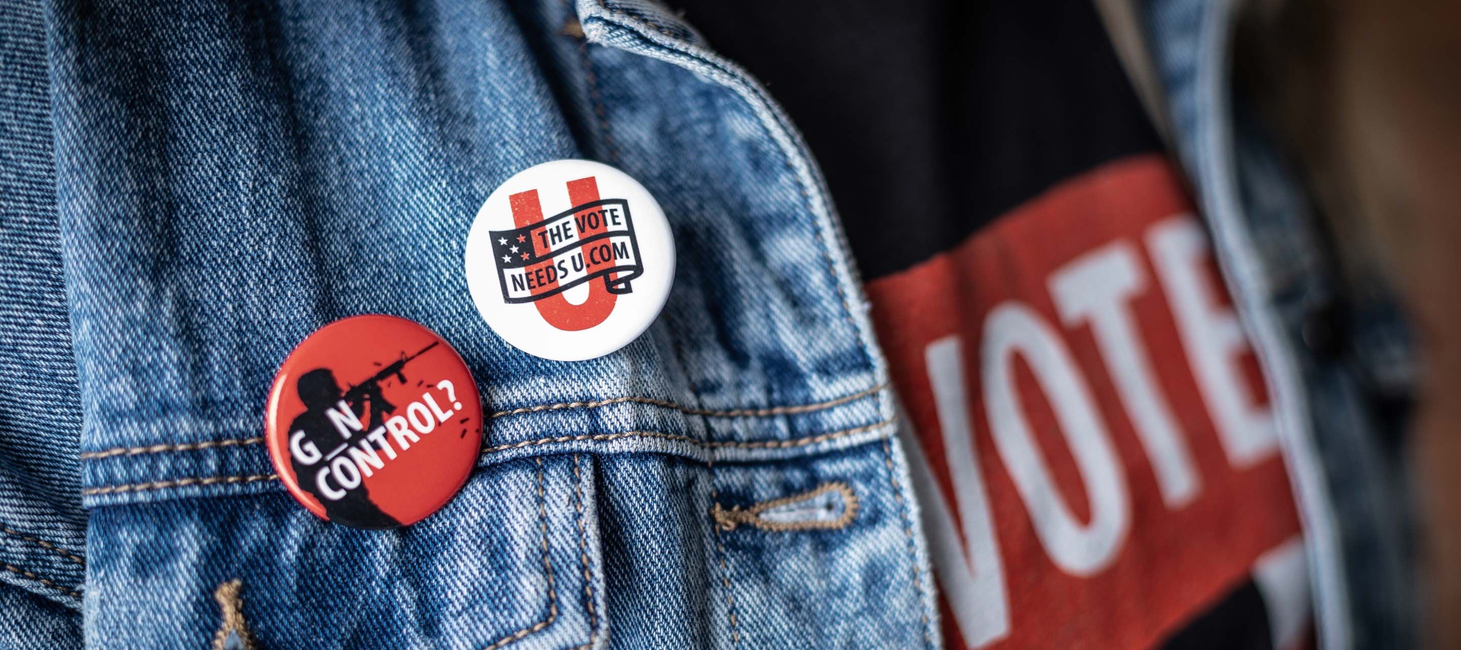 Person wearing The Vote Needs U pins.