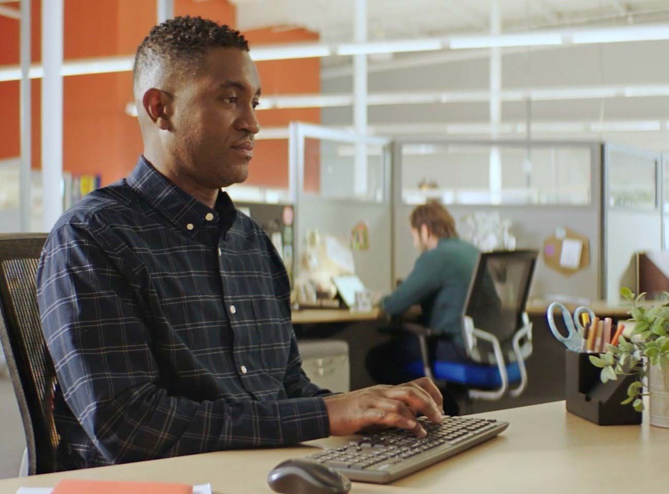 A man sitting at his work desk and typing on his keyboard. Click to view the video.