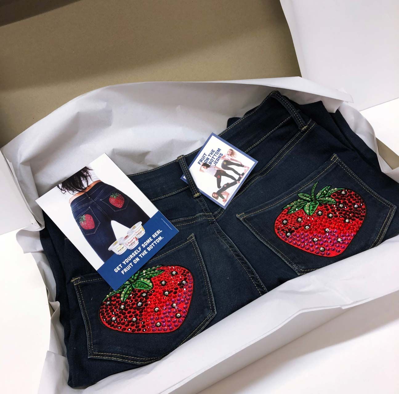 Photograph of jeans with strawberries bedazzled on the back pockets.
