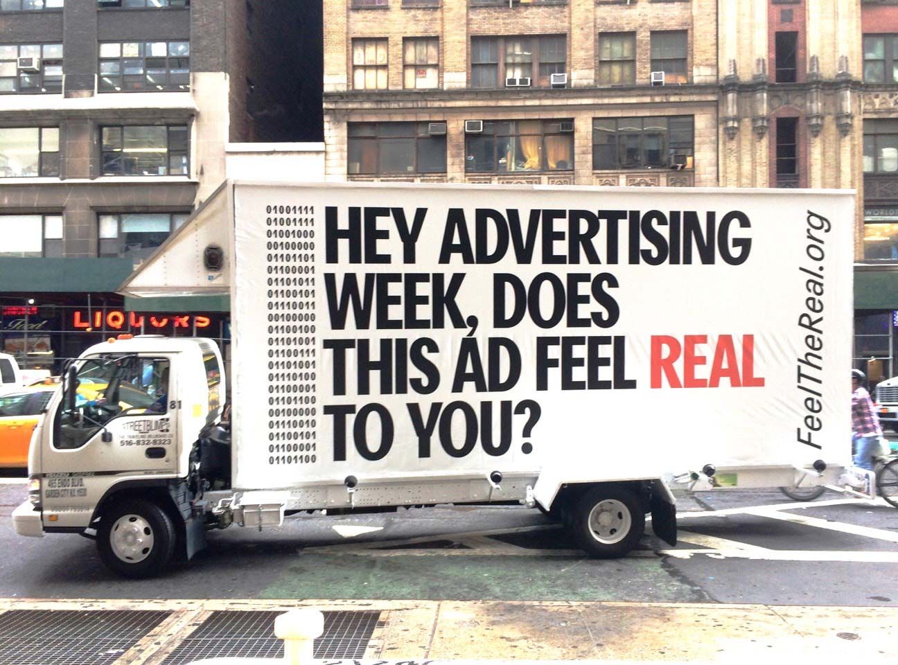Truck with advertisement on it, "Hey Advertising Week, does this ad feel real to you?"