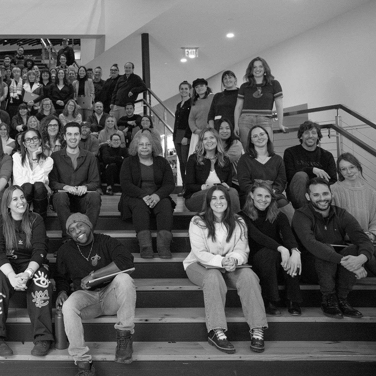 Photograph of the P+N employees seated on the stairs in the office.