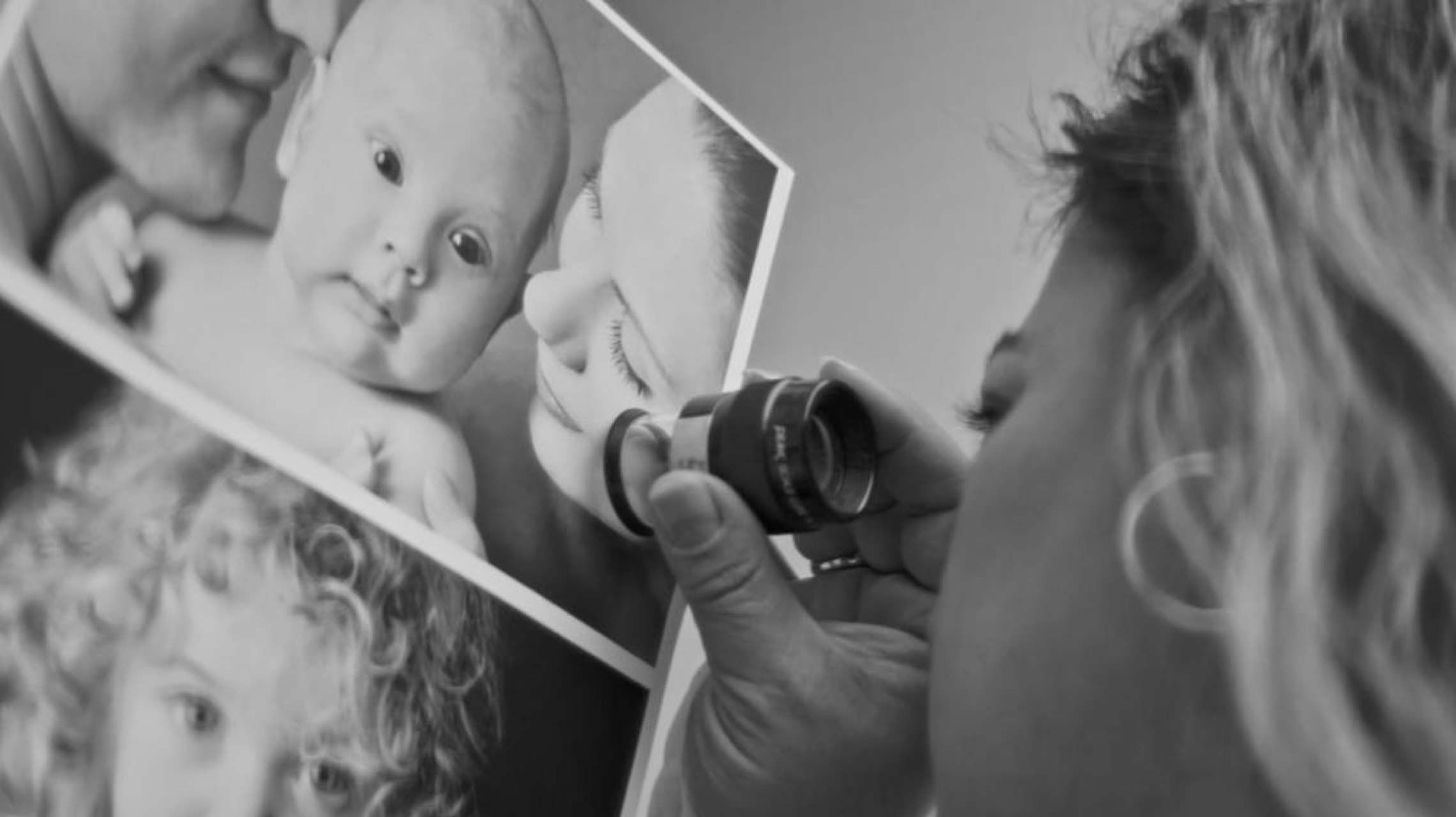 Woman looking at prints of family photos. Click to watch the video.