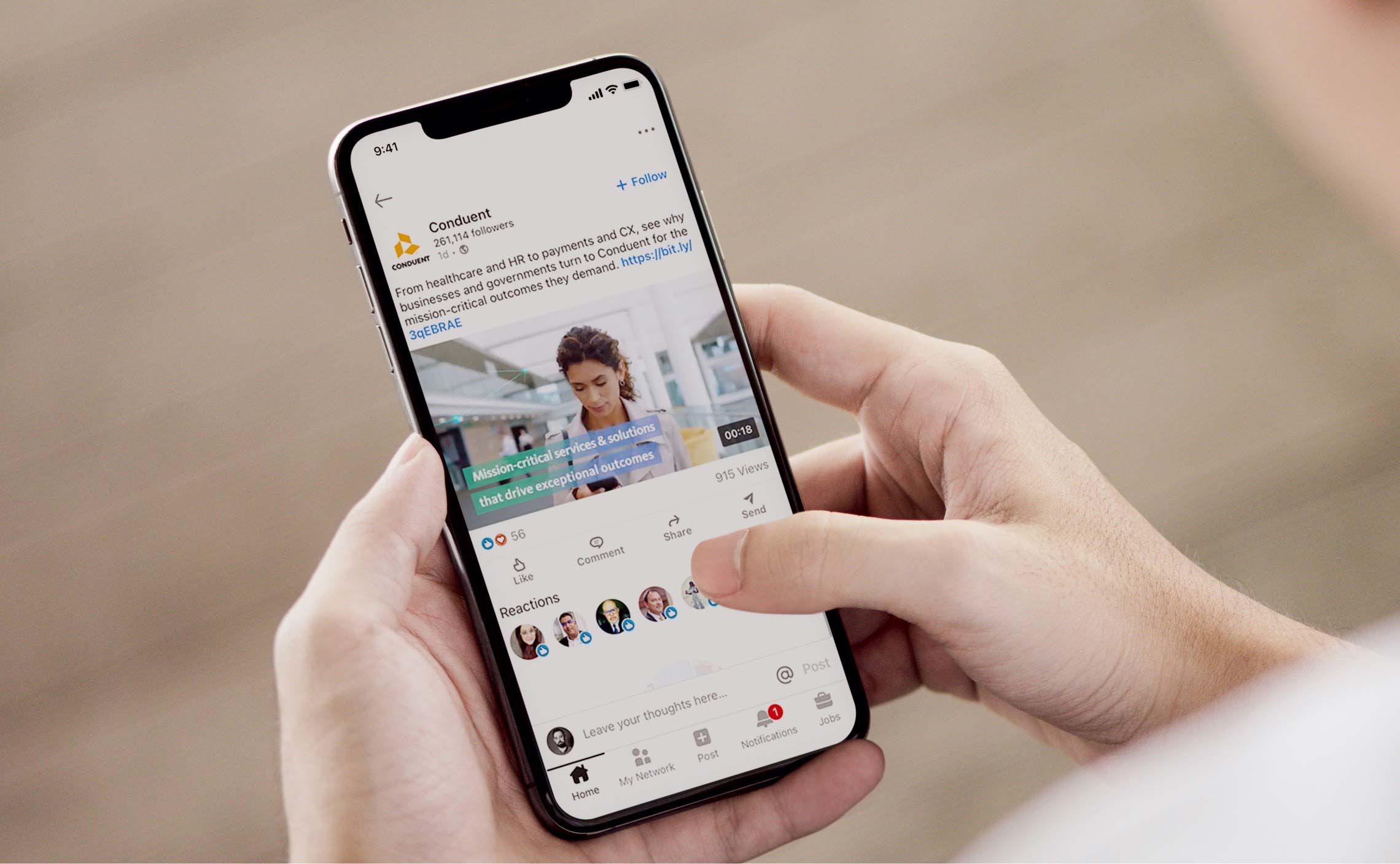 Photograph of a person viewing the Conduent LinkedIn page on their phone.