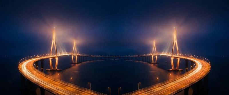 A cable-stayed bridge lit at night spanning dark water