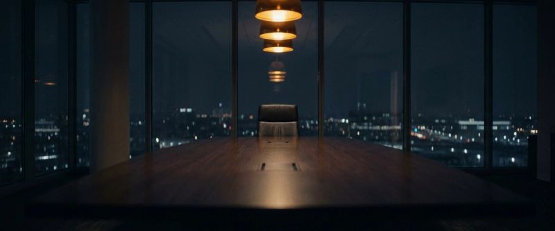 A long boardroom table under warm pendant lighting
