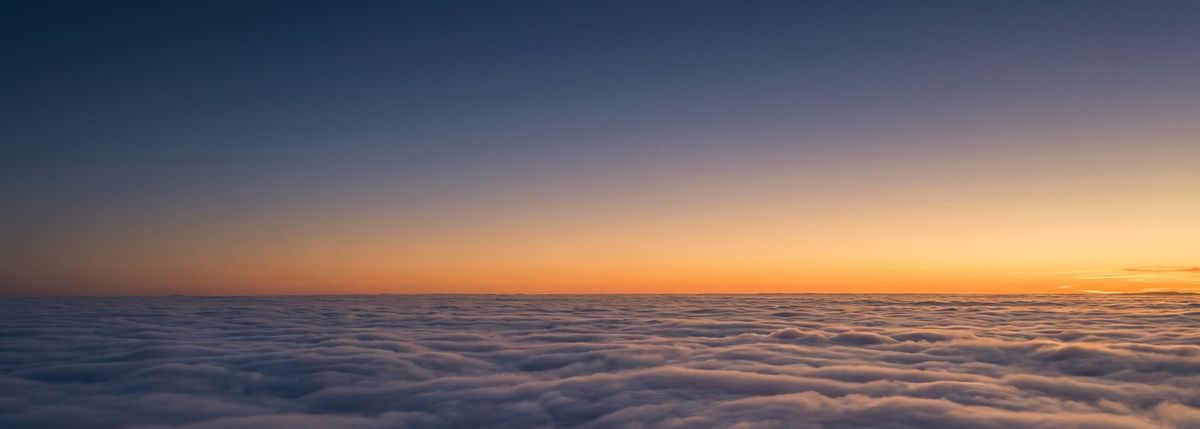An aerial view above a flat layer of cloud at dusk