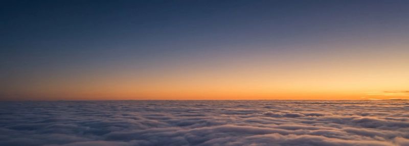 An aerial view above a flat layer of cloud at dusk
