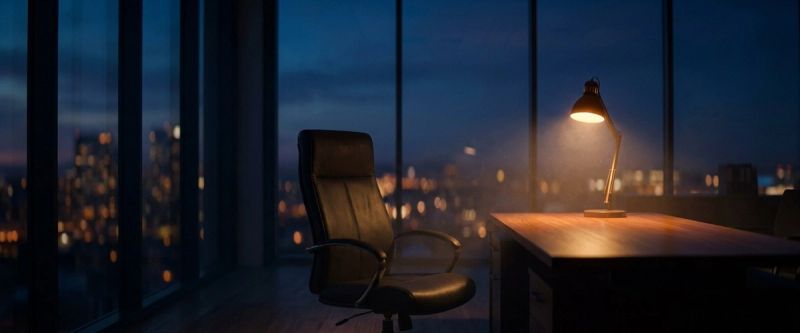 An executive office at dusk, one chair turned to the windows