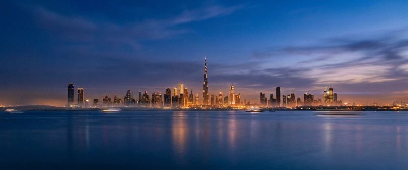 The Dubai skyline at blue hour seen across still water