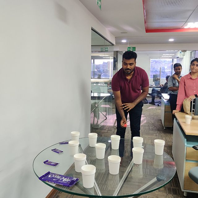Colleagues playing a cup-stacking game at a fun-at-work event in the Inspira office