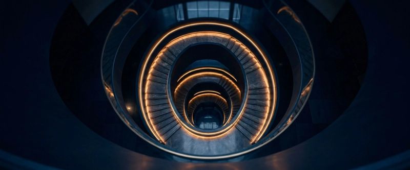 A spiral staircase in a dark corporate atrium seen from above