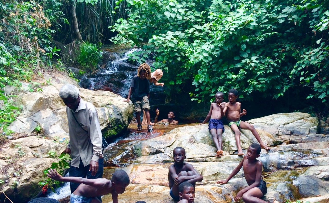 Waterfall in Ghana with the waterfall's keeper and children