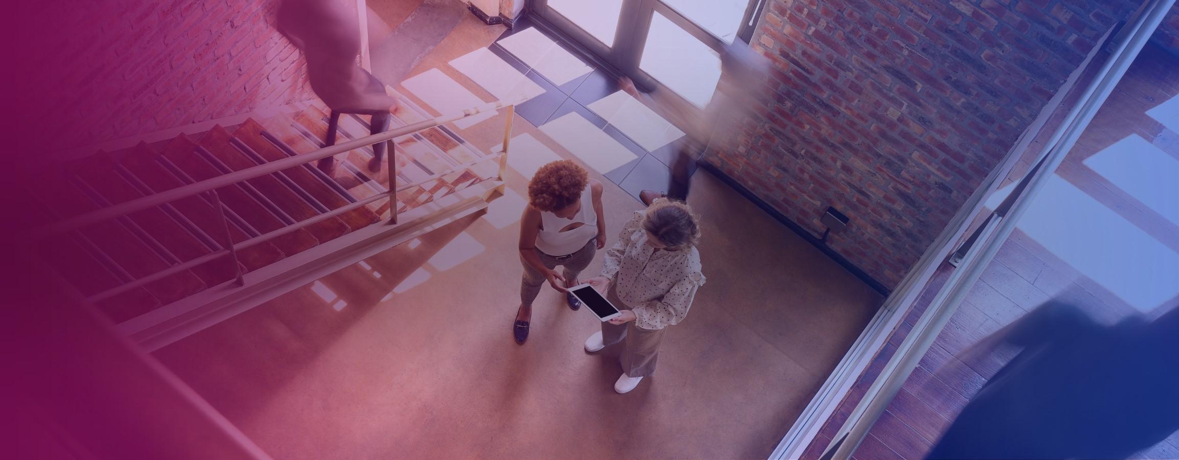 Office stock image, with people conversing at the bottom of a staircase