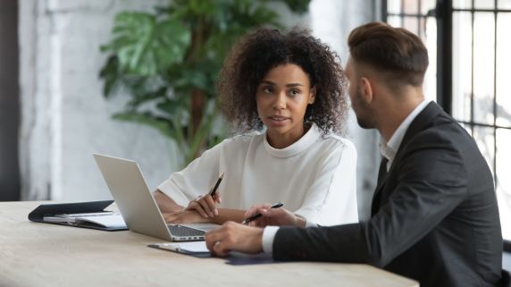 corporate stock image of two colleagues talking whilst working on a laptop
