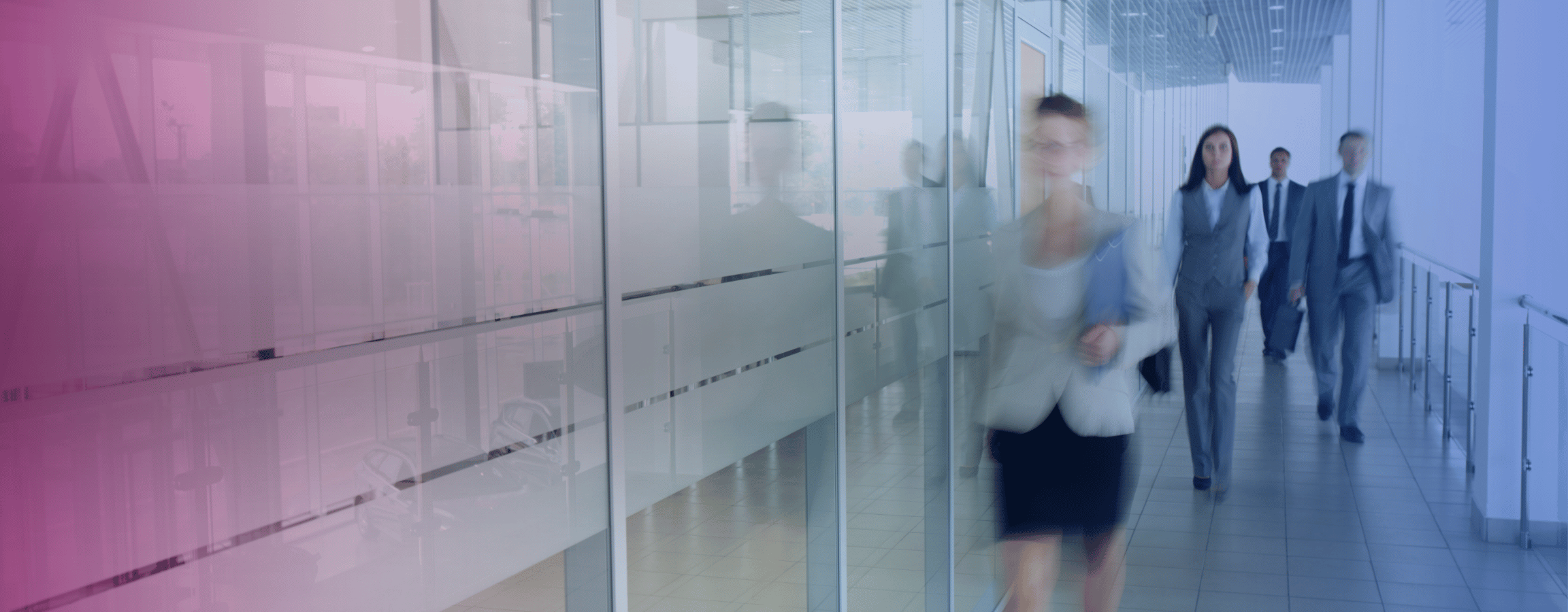 Ihmisiä kävelee lasiseinän vieressä toimistossa