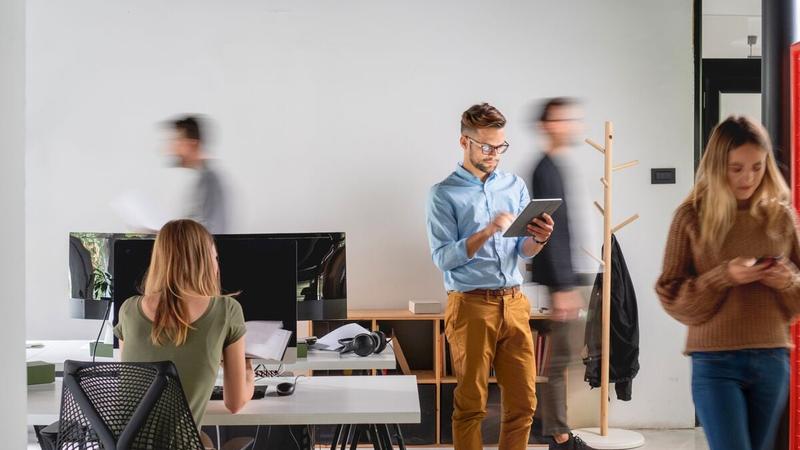 Man on a tablet in a busy office