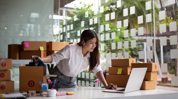 stock image of businesswoman packaging boxes