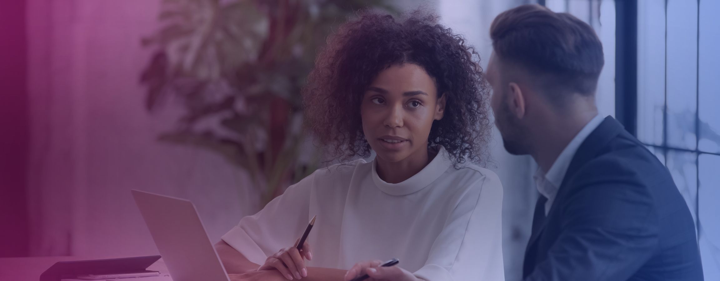 corporate stock image of two colleagues talking whilst working on a laptop