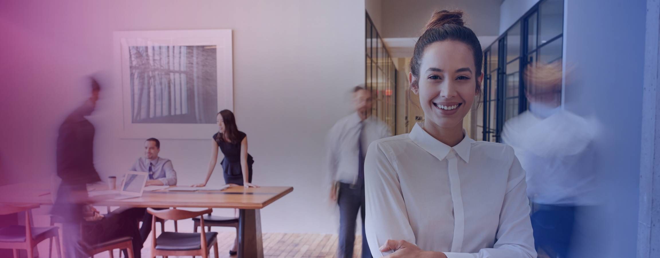 Kvinde, der smiler til kameraet på et travlt kontor