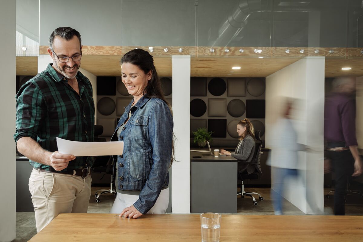 Man and woman reading a document in a busy office