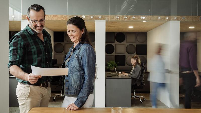 Man and woman reading a document in a busy office