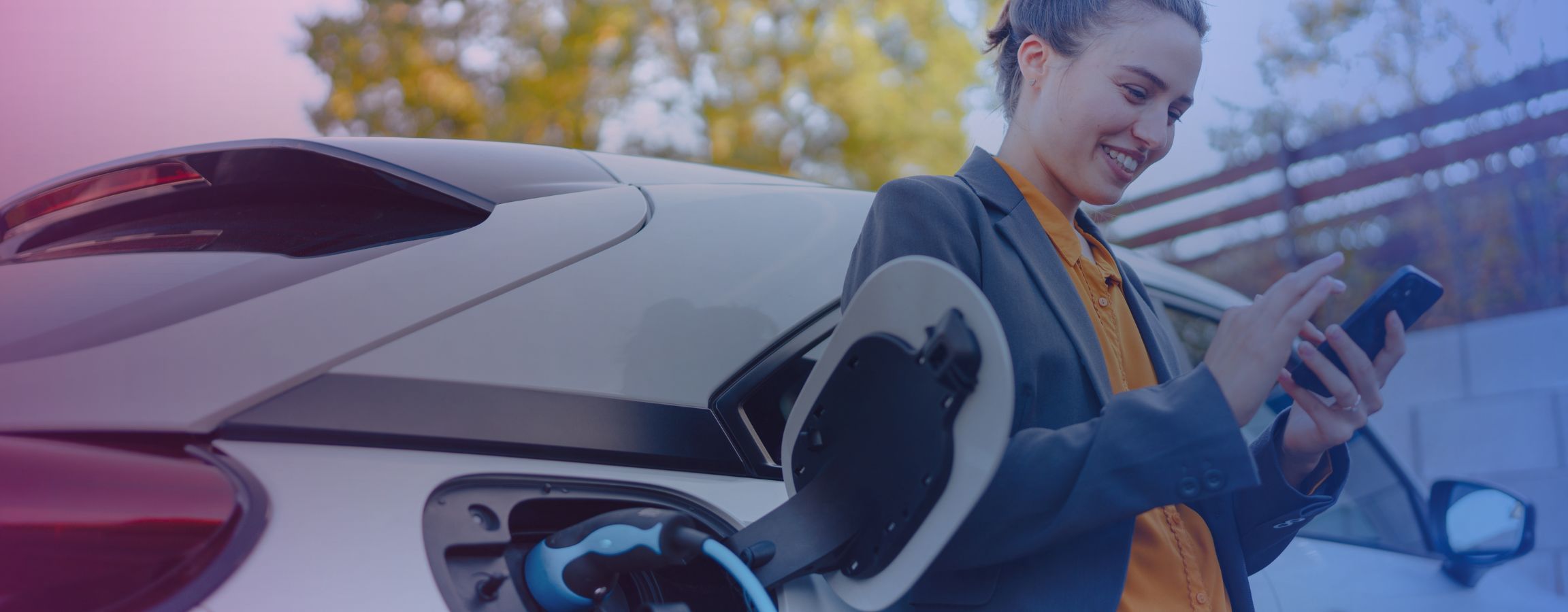 A woman on her phone whilst she waits for her electric car to charge