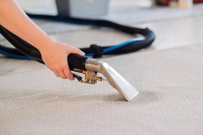 Woman's hands cleaning carpet with steam cleaner