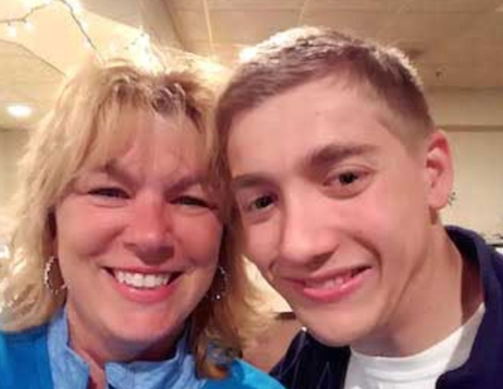 Two people smiling at the camera indoors, wearing casual clothing.