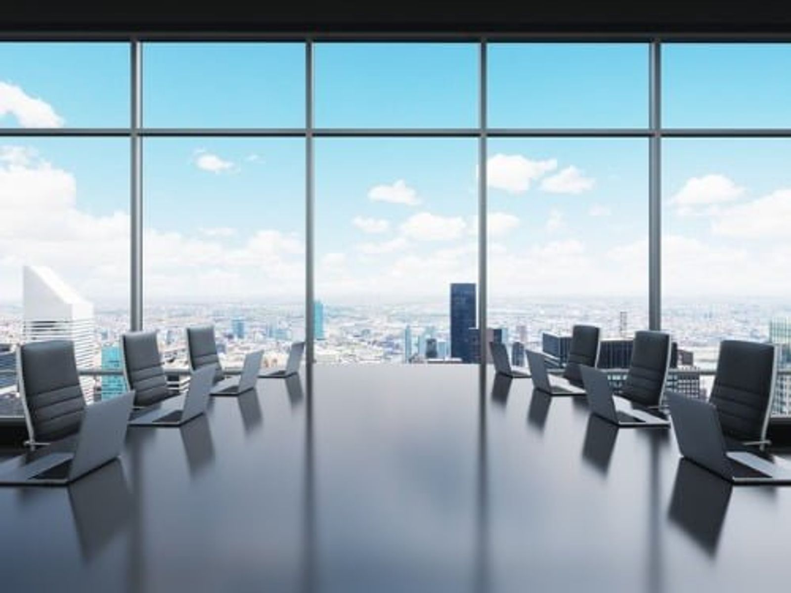 Modern conference room with floor-to-ceiling windows overlooking cityscape and sky.