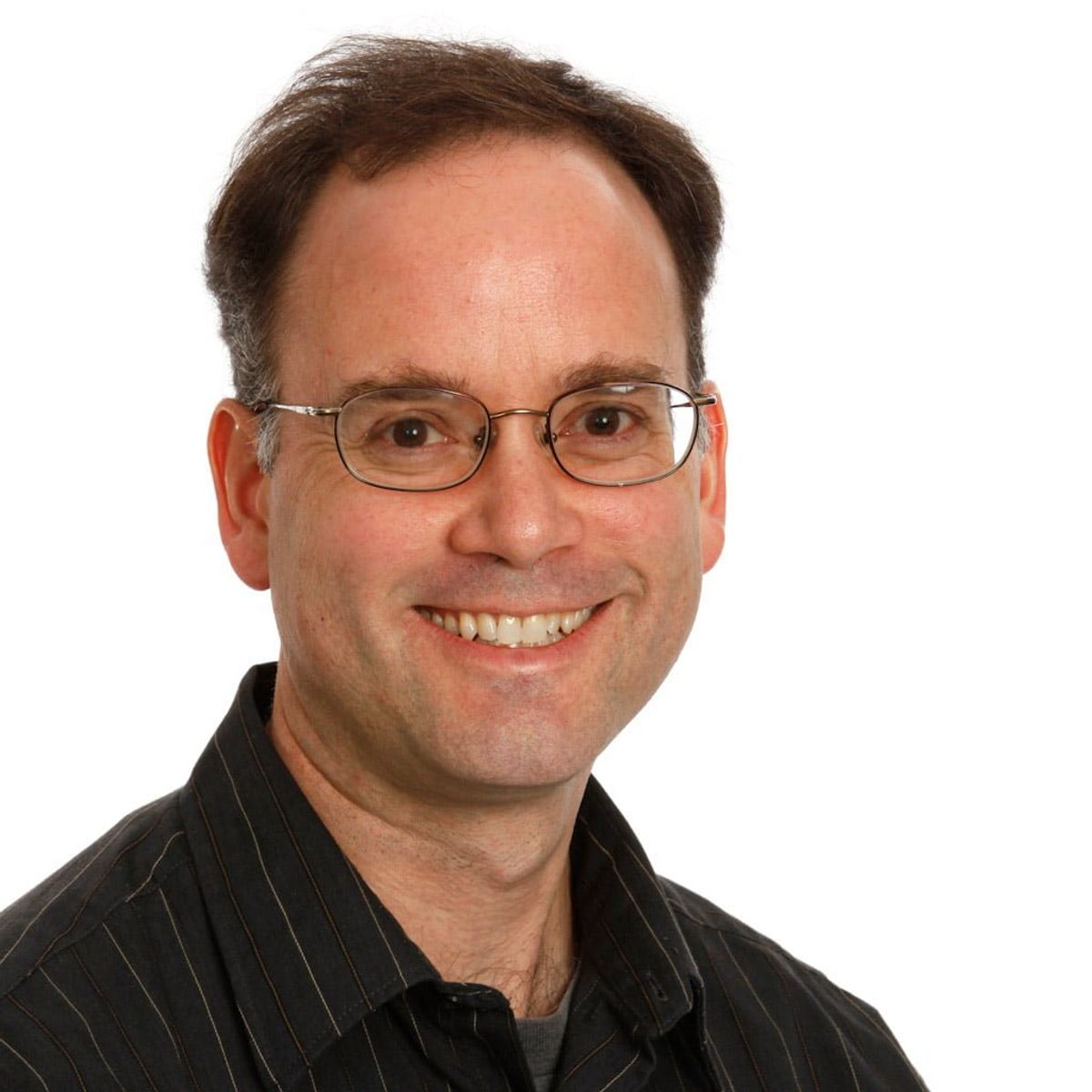 Professional headshot of a man wearing glasses and a dark pinstriped shirt, smiling at camera.