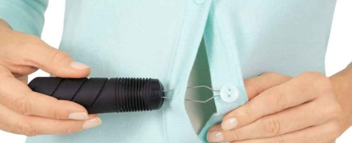 Person in light blue shirt holding black cylindrical medical device or tool.