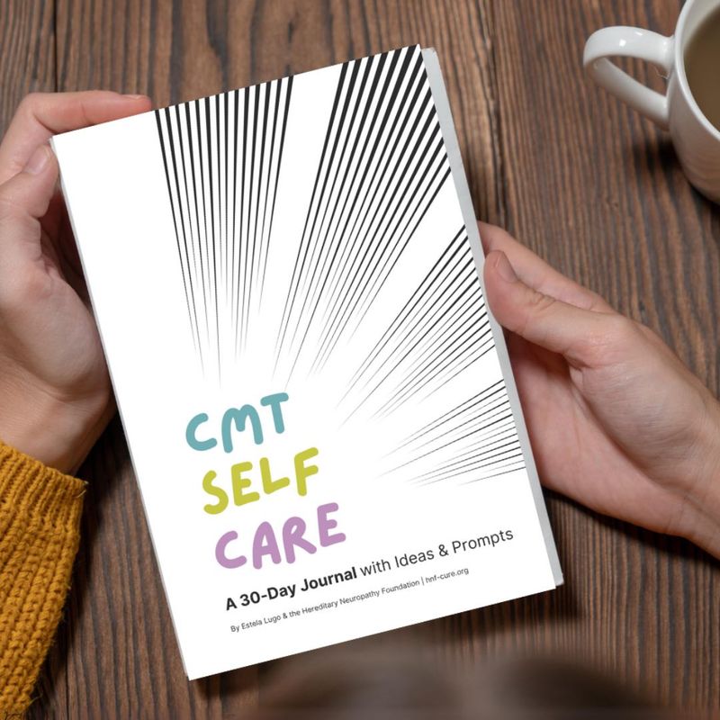 Persona sosteniendo el libro "Autocuidado de CMT: un diario de 30 días con ideas & sugerencias" sobre una superficie de madera, junto a una taza.