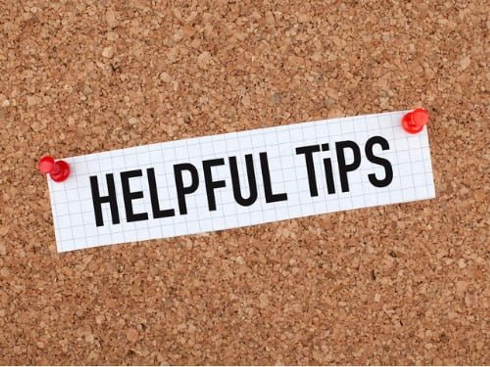 White lined paper strip reading "HELPFUL TIPS" pinned to cork board with red pushpins