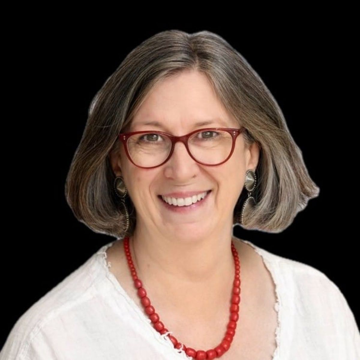 Professional headshot of woman with gray hair, glasses, and red beaded necklace against black background.